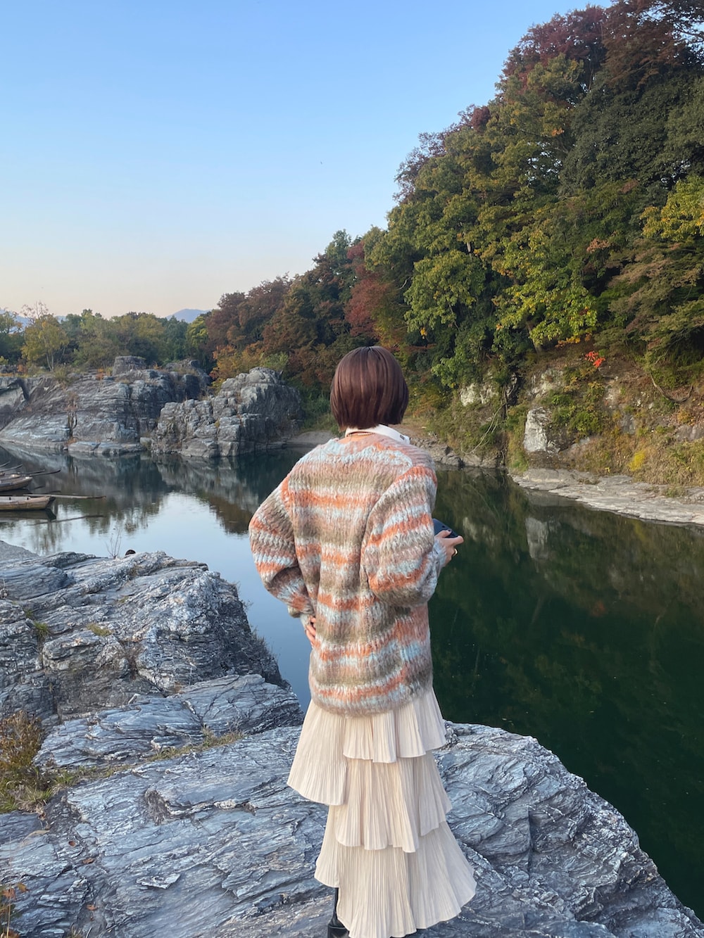 オレンジ系のカーディガン/ボレロ、ブラック系のブーツを着用したレディースの春コーディネートの2枚目の写真