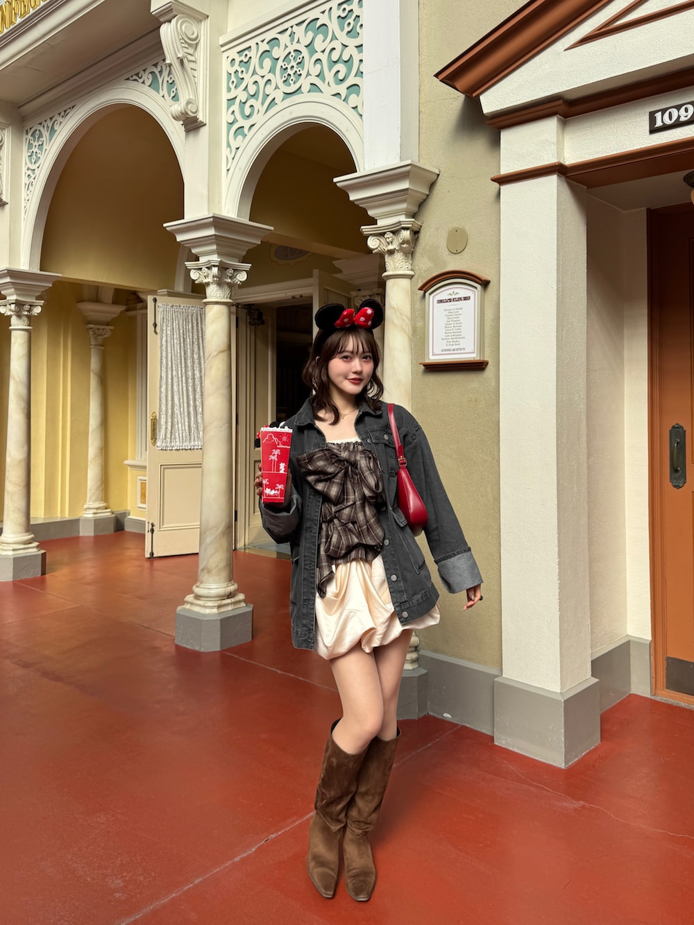 ブラック系のデニムジャケット、ブラウン系のキャミソール、ブラウン系のブーツを着用したレディースの春コーディネートの3枚目の写真