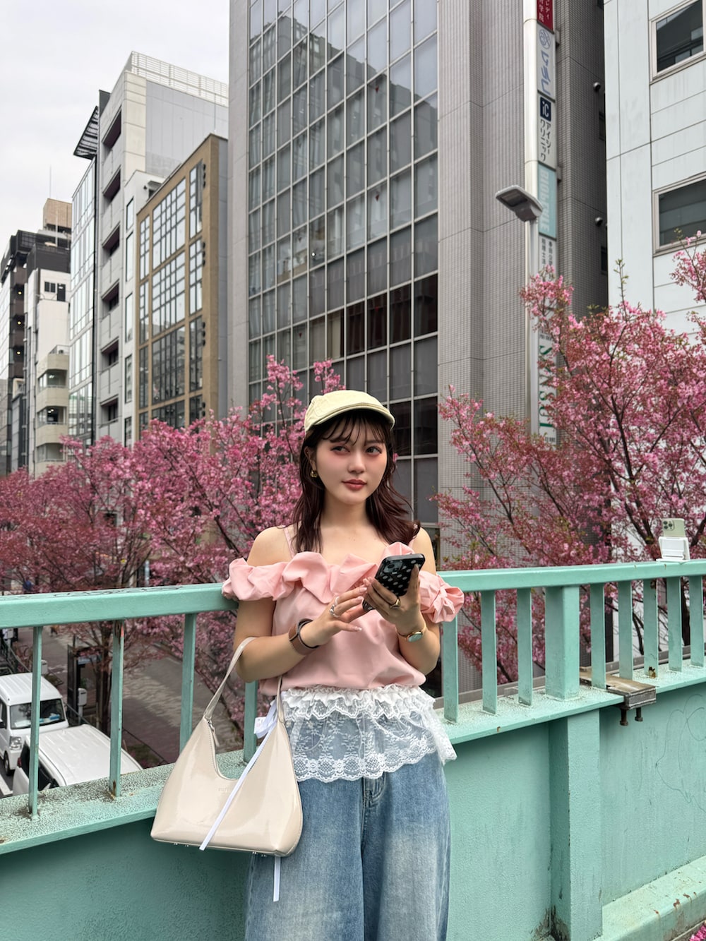 ベージュ系のハンドバッグ、ピンク系のTシャツ/カットソー、ホワイト系のスカートを着用したレディースの春コーディネートの4枚目の写真