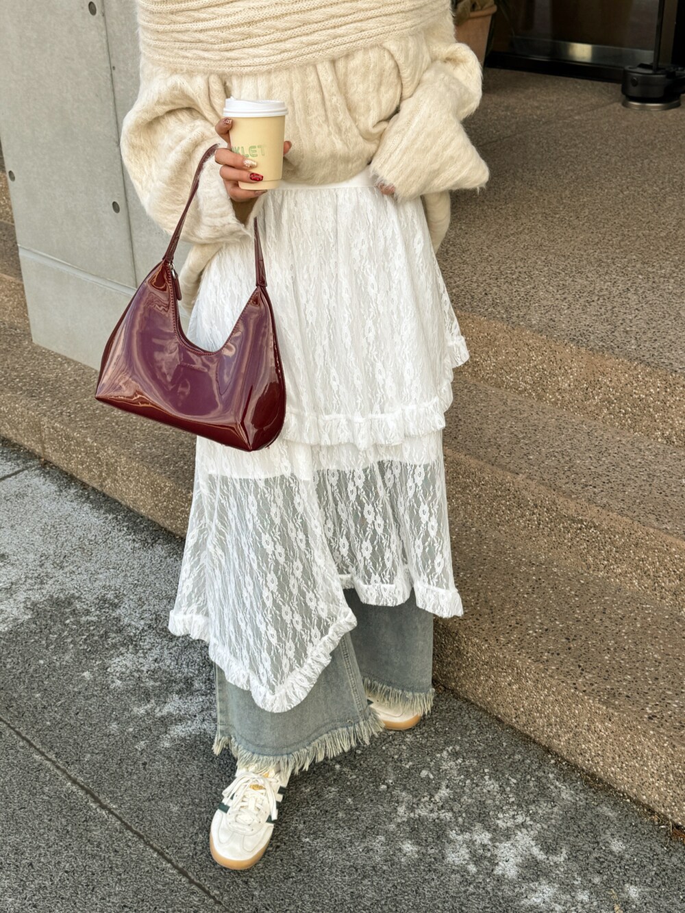 レッド系のハンドバッグ、ブルー系のデニムパンツを着用したレディースの冬コーディネートの2枚目の写真