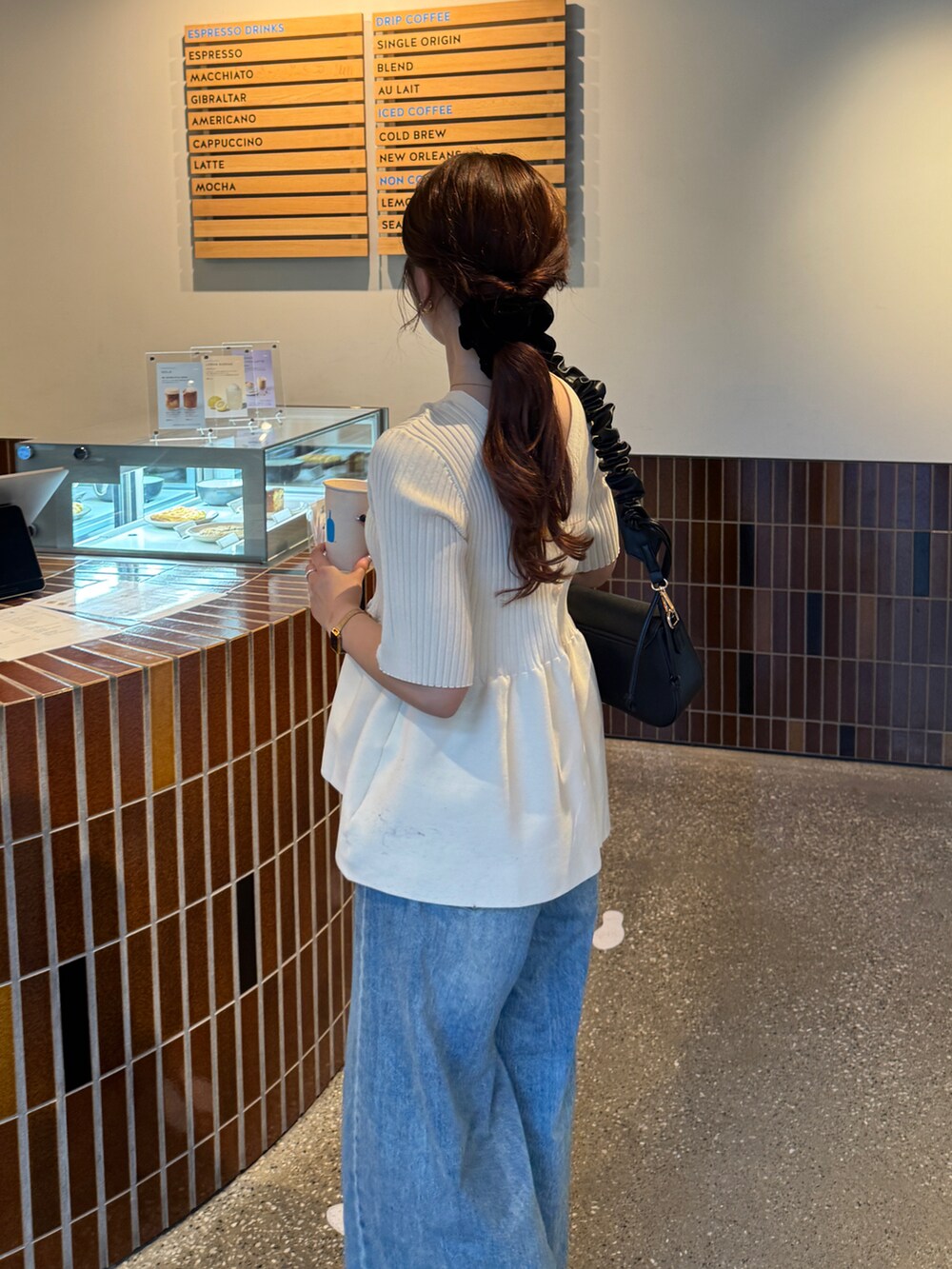 ホワイト系のニット/セーター、ブラック系のパンプスを着用したレディースの夏コーディネートの2枚目の写真