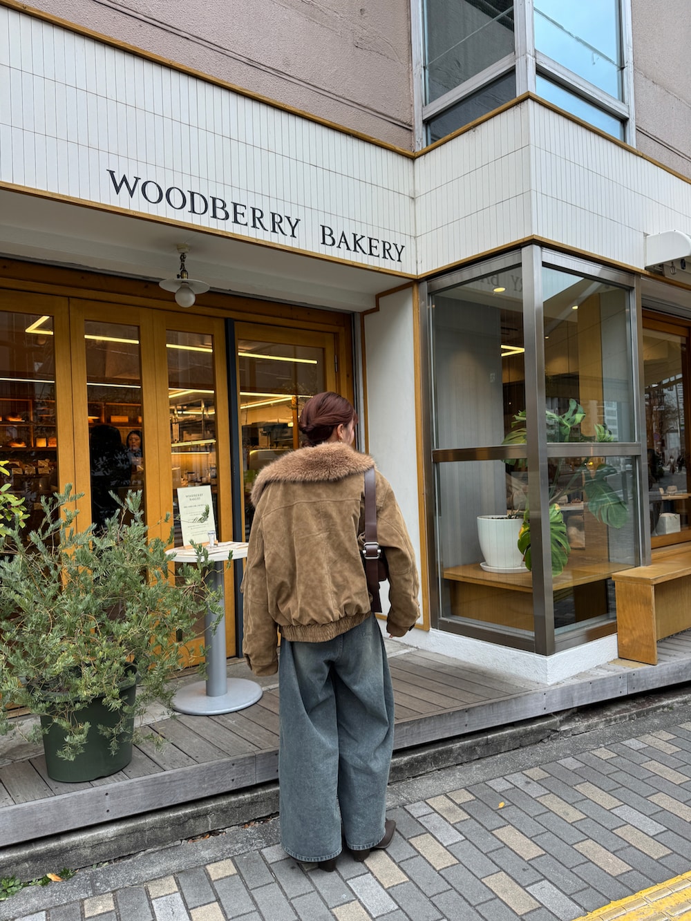 ブルー系のデニムパンツ、ベージュ系のブルゾン、レッド系のニット/セーターを着用したレディースの冬コーディネートの3枚目の写真