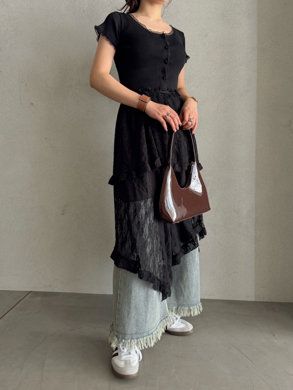 ブラウン系のハンドバッグ、ブラック系のスカート、ブルー系のデニムパンツを着用したレディースの春コーディネートの3枚目の写真