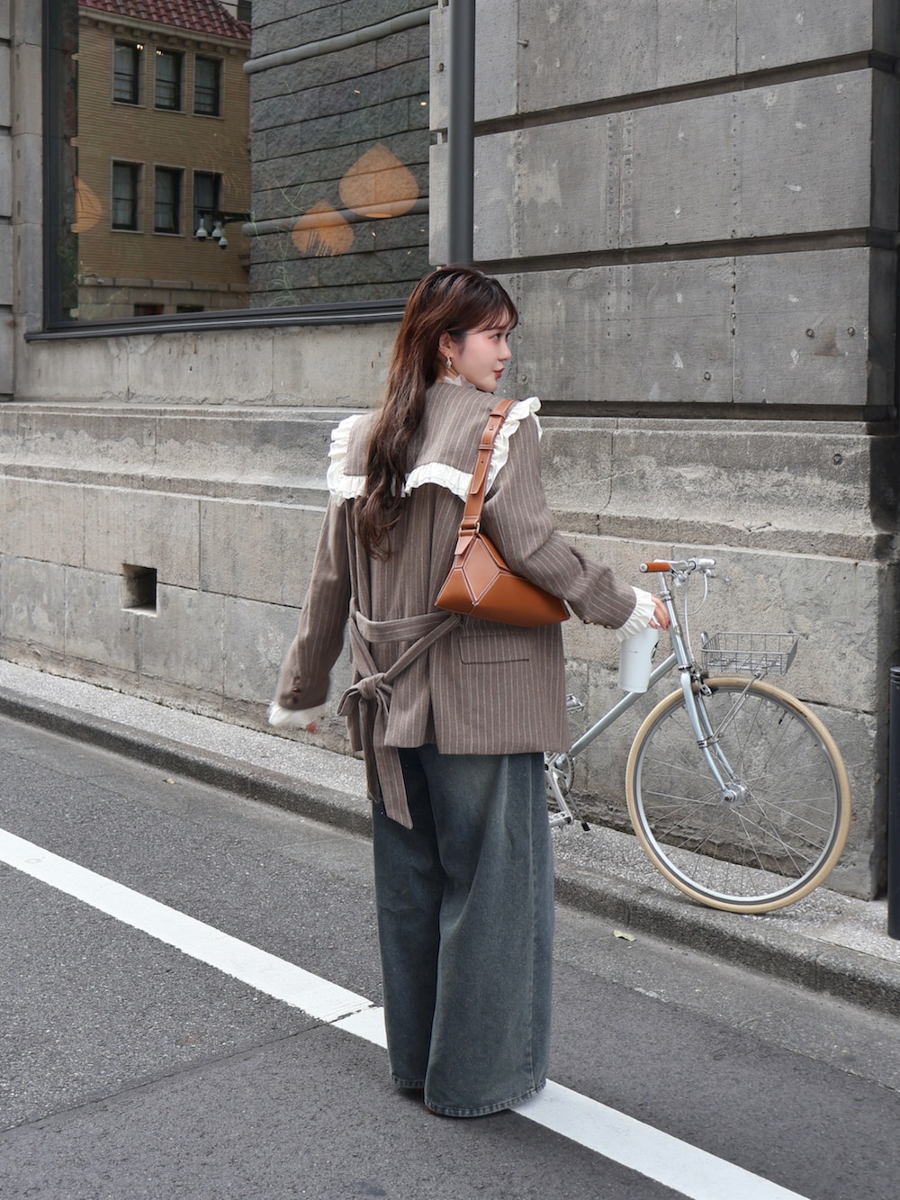 ブルー系のデニムパンツ、ベージュ系のテーラードジャケット、ブラウン系のショルダーバッグを着用したレディースの夏コーディネートの4枚目の写真