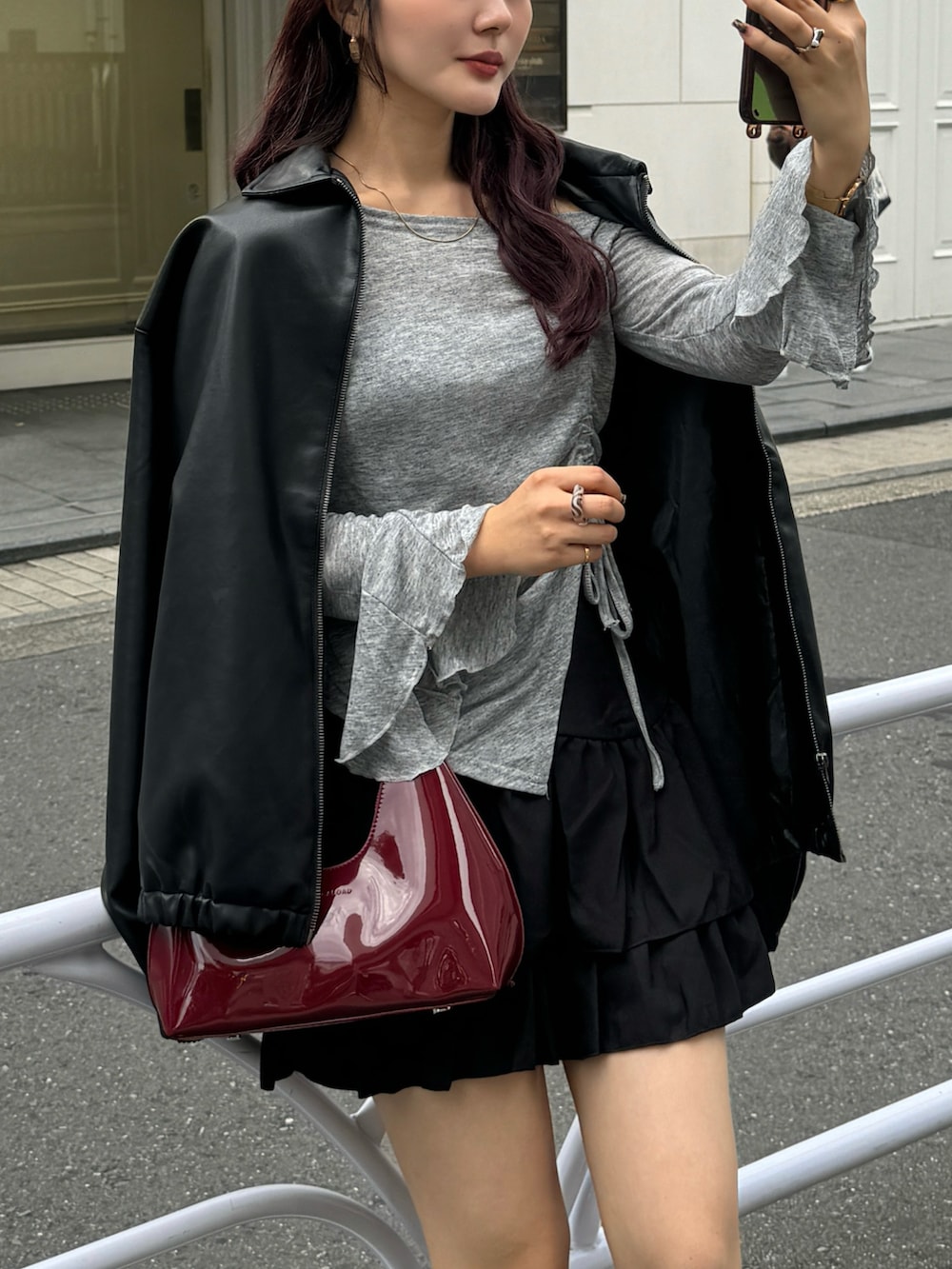 レッド系のハンドバッグ、グレー系のTシャツ/カットソー、ブラック系のジャケット/アウターを着用したレディースの秋コーディネートの4枚目の写真