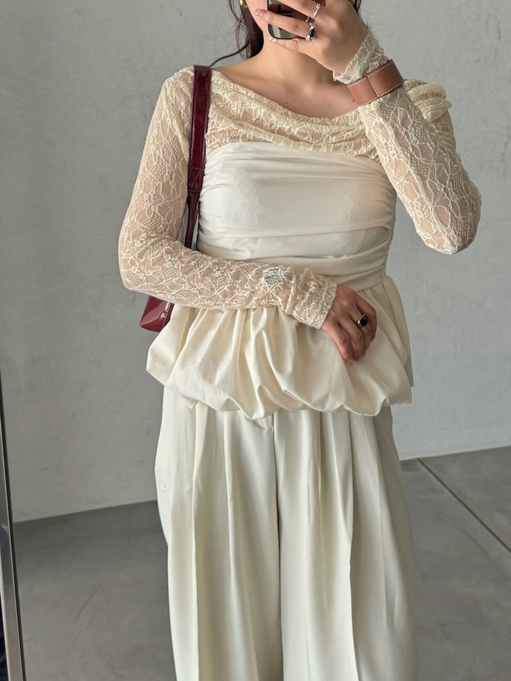 レッド系のハンドバッグ、ホワイト系のスラックス、ホワイト系のシャツ/ブラウスを着用したレディースの春コーディネートの3枚目の写真