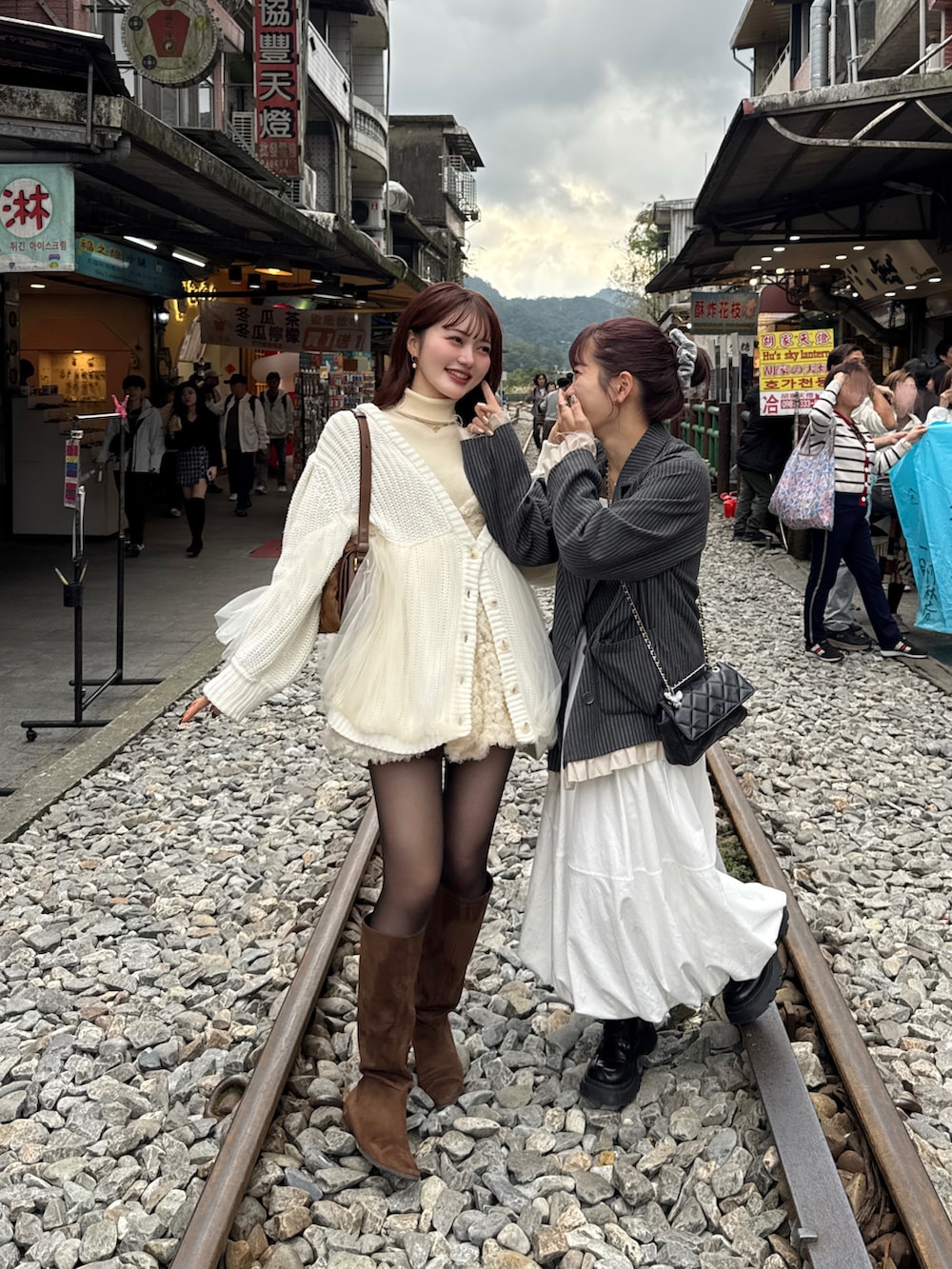 グレー系のテーラードジャケット、ホワイト系のカーディガン/ボレロ、ブラウン系のブーツを着用したレディースの冬コーディネートの3枚目の写真