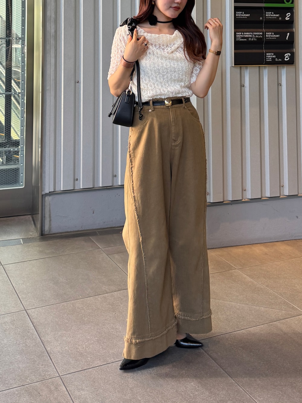 ブラック系のパンプス、ブラック系のハンドバッグ、ホワイト系のTシャツ/カットソーを着用したレディースの夏コーディネートの5枚目の写真