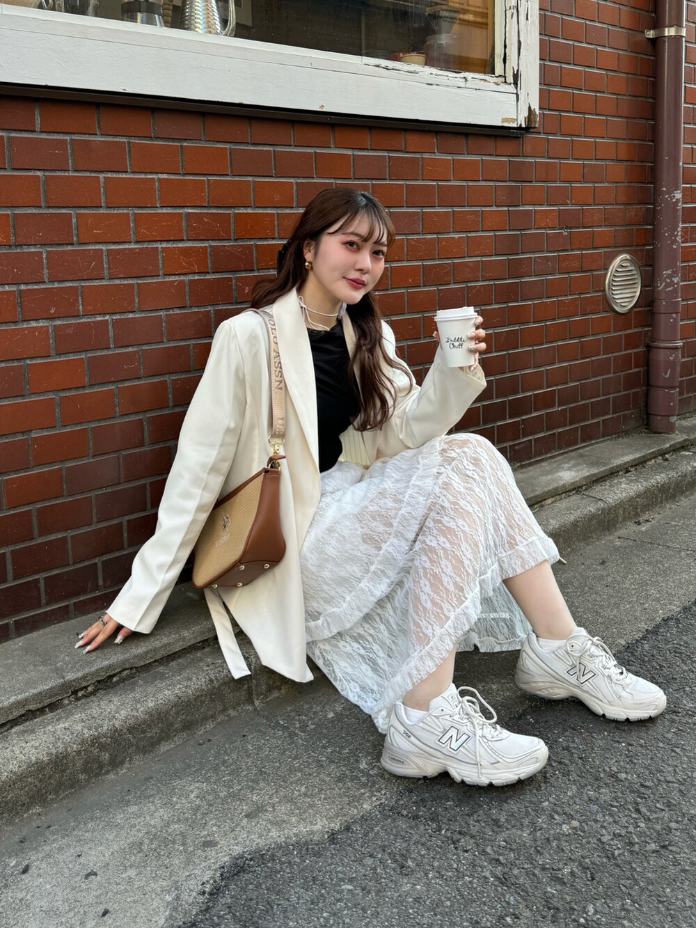 ブラウン系のショルダーバッグ、ホワイト系のスカート、ベージュ系のスニーカーを着用したレディースの春コーディネートの4枚目の写真