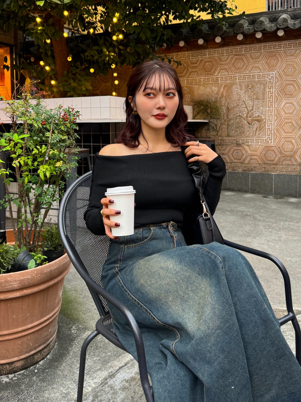 ブラック系のニット/セーター、ブラウン系のハンドバッグ、ブラック系のブーツを着用したレディースの秋コーディネートの3枚目の写真