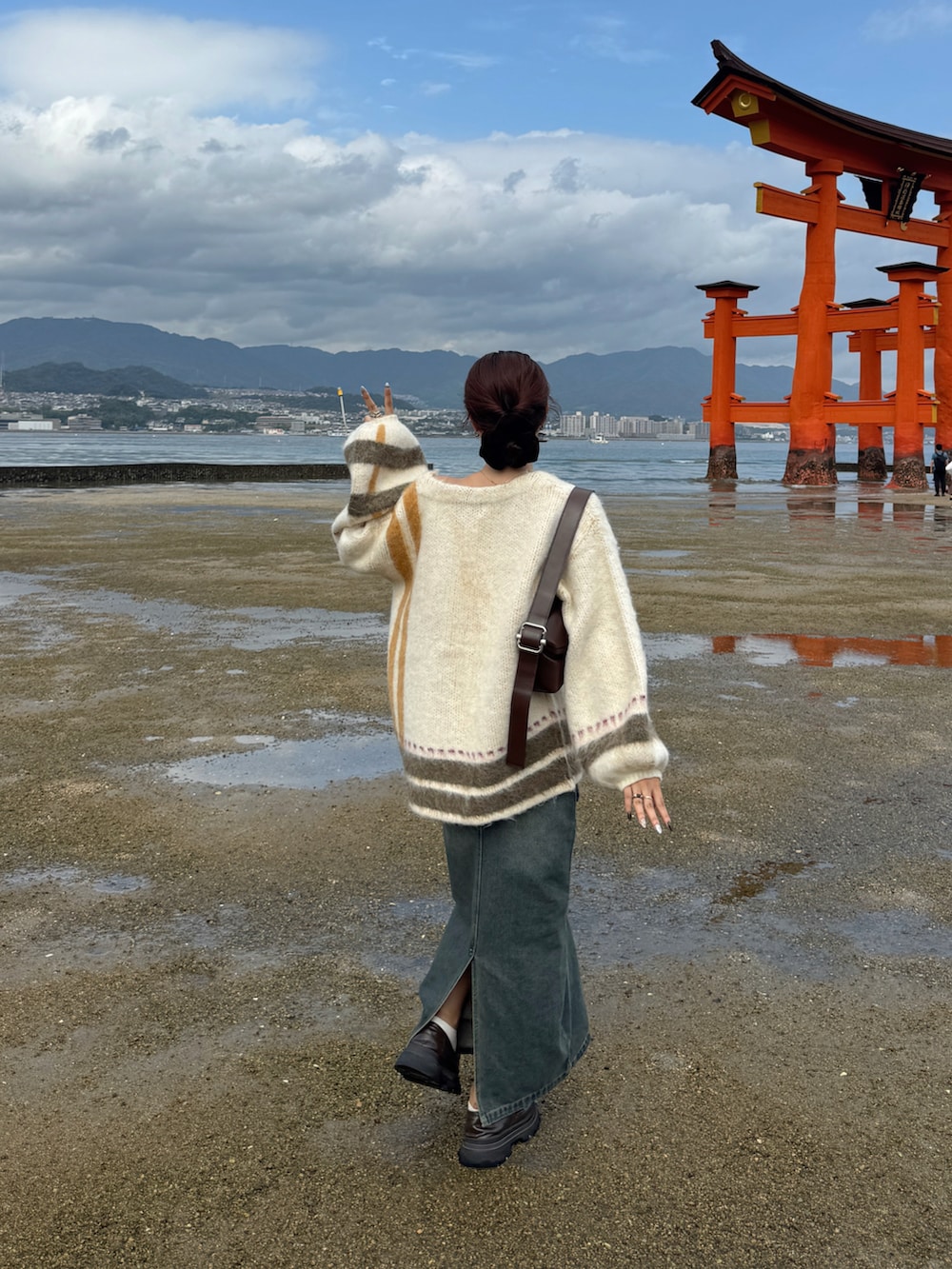 ホワイト系のカーディガン/ボレロ、ブラウン系のショルダーバッグ、ブルー系のデニムスカートを着用したレディースの秋コーディネートの3枚目の写真