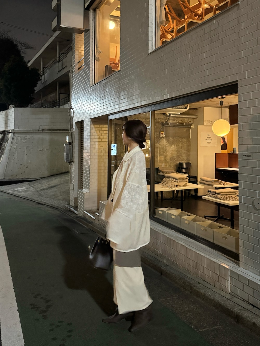 ホワイト系のテーラードジャケット、ブラウン系のブーツを着用したレディースの春コーディネートの3枚目の写真