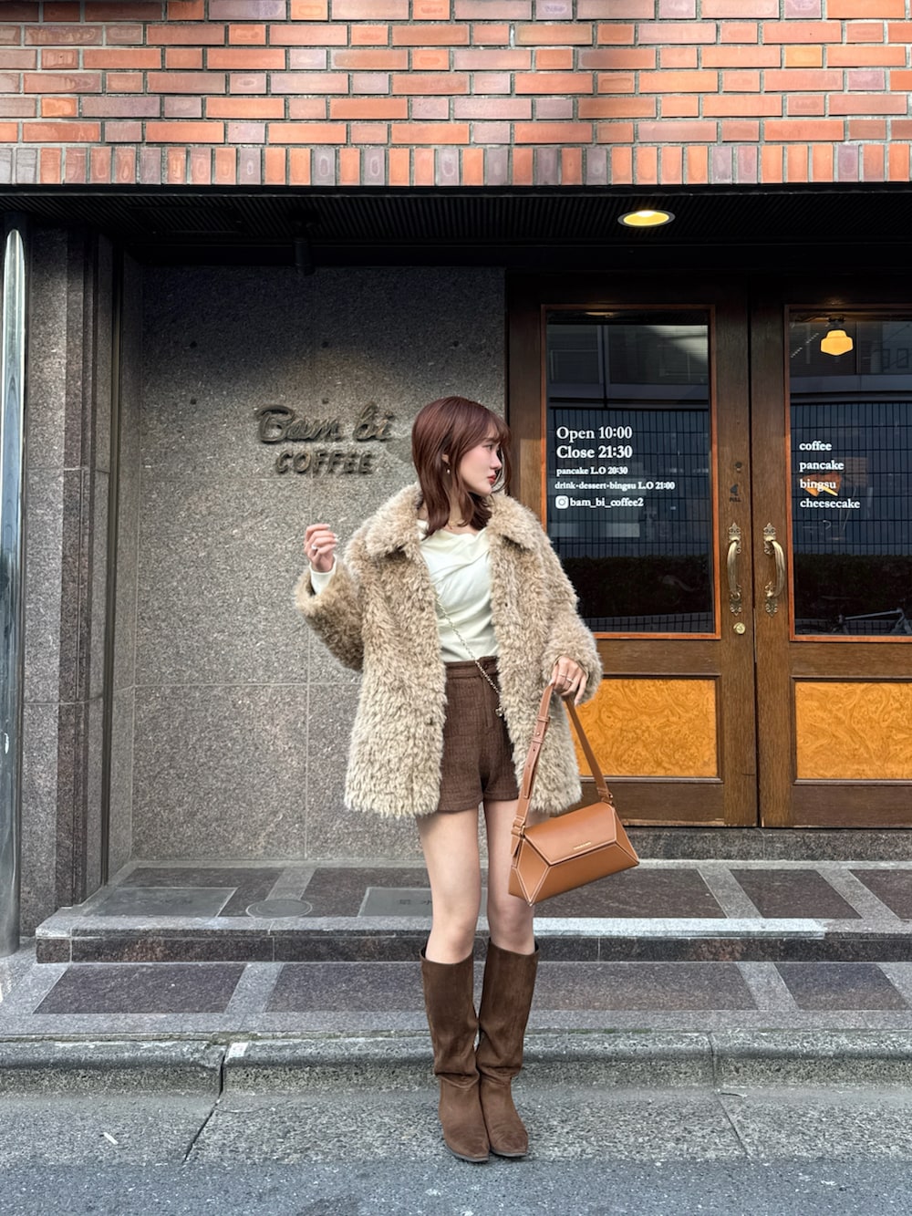 ブラウン系のブーツ、ブラウン系のショルダーバッグ、ベージュ系のカバーオールを着用したレディースの冬コーディネートの3枚目の写真