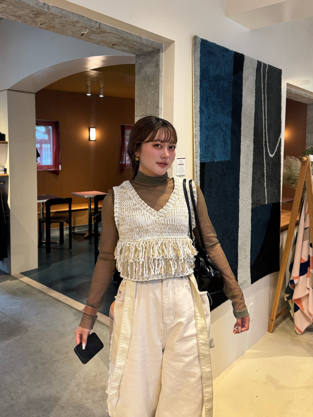 ブラック系のパンプス、ホワイト系のデニムパンツ、ホワイト系のベストを着用したレディースの夏コーディネートの2枚目の写真