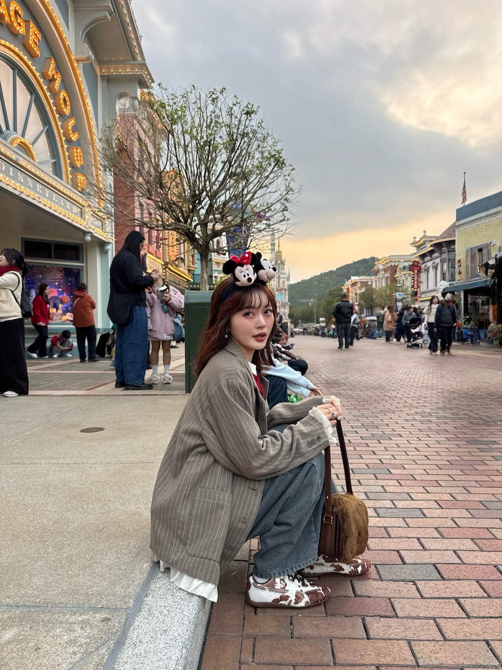 ブラウン系のテーラードジャケット、ブルー系のデニムパンツ、ブラウン系のスニーカーを着用したレディースの冬コーディネートの2枚目の写真