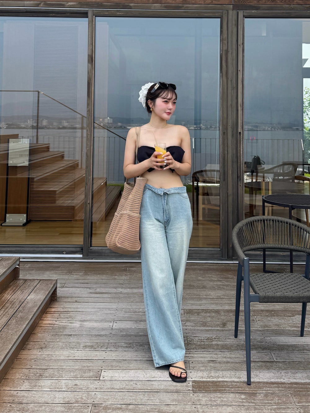 ブルー系のデニムパンツ、ブラウン系のサンダルを着用したレディースの夏コーディネートの3枚目の写真