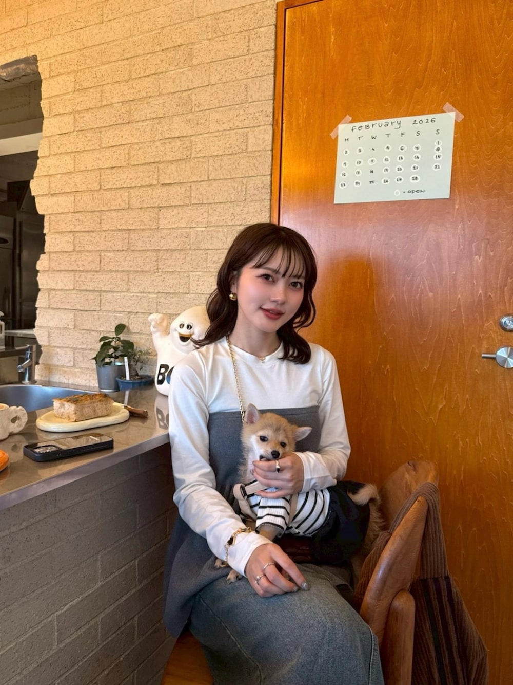 グレー系のトップス、ブルー系のデニムスカート、ブラウン系のスニーカーを着用したレディースの冬コーディネートの3枚目の写真