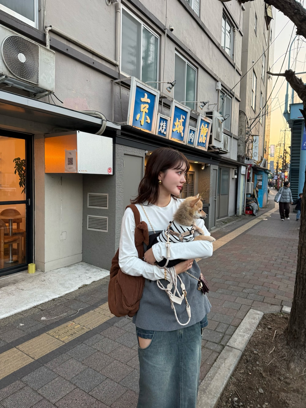 グレー系のトップス、ブルー系のデニムスカート、ブラウン系のスニーカーを着用したレディースの冬コーディネートの2枚目の写真