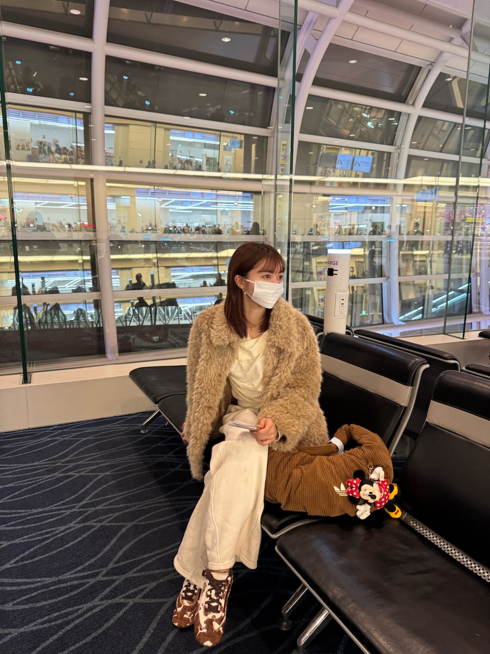 ブラウン系のスニーカー、ベージュ系のカバーオール、ホワイト系のニット/セーターを着用したレディースの冬コーディネートの2枚目の写真