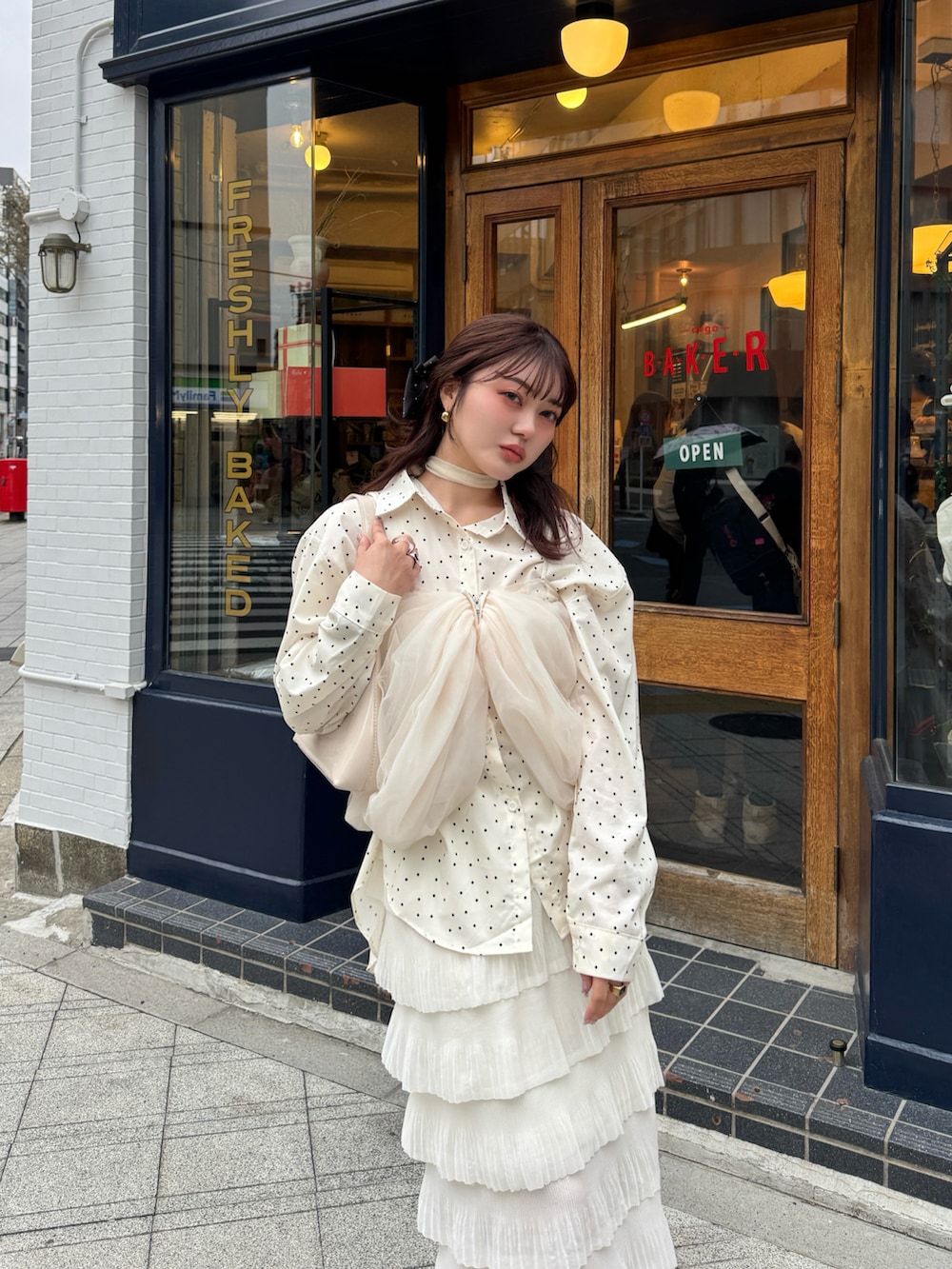 レッド系のハンドバッグ、ベージュ系のスカート、ホワイト系のシャツ/ブラウスを着用したレディースの春コーディネートの3枚目の写真