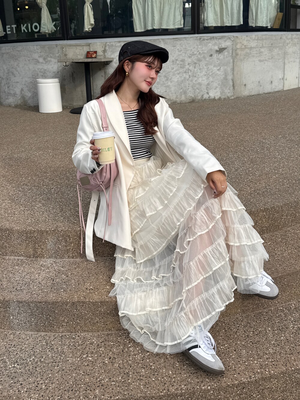 ホワイト系のスカート、ホワイト系のスニーカー、ホワイト系のテーラードジャケットを着用したレディースの春コーディネートの5枚目の写真