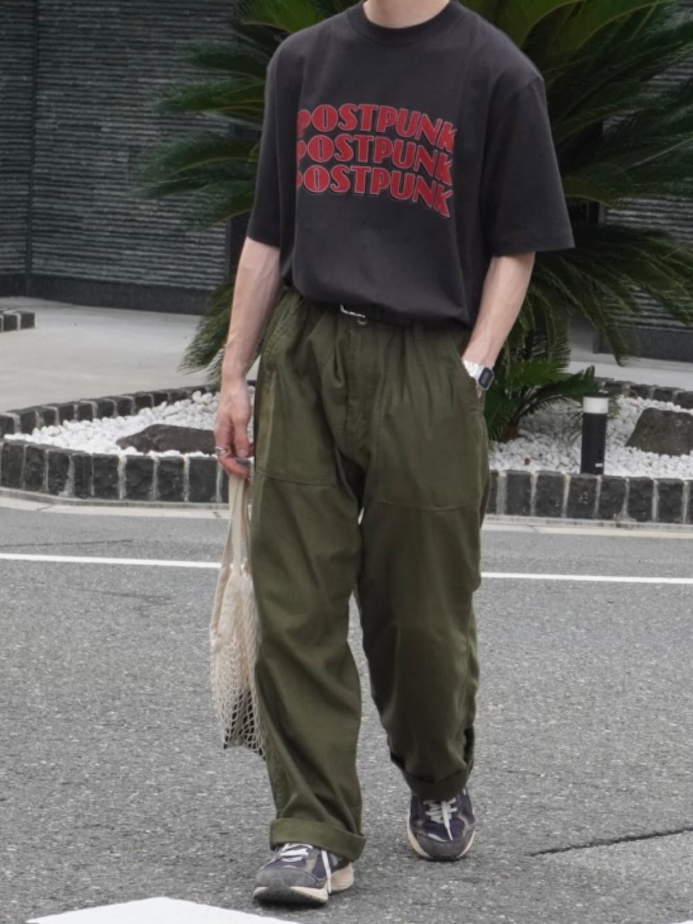 グリーン系のカーゴパンツ、ホワイト系のバッグ、ブラック系のスニーカーを着用したメンズの夏コーディネートの2枚目の写真