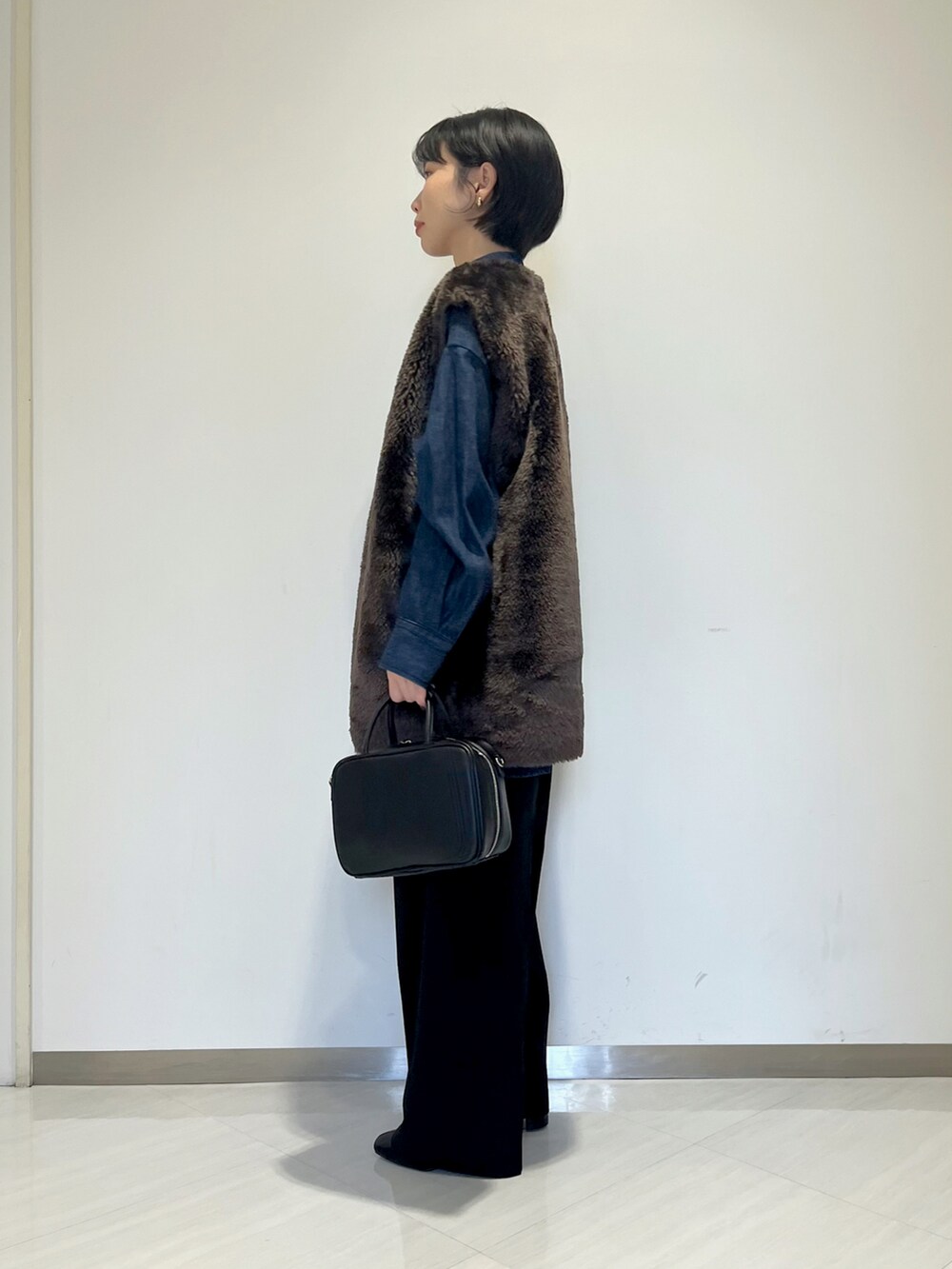ブラック系のショルダーバッグ、ブラック系のスラックス、ブルー系のシャツ/ブラウスを着用したレディースの冬コーディネートの2枚目の写真