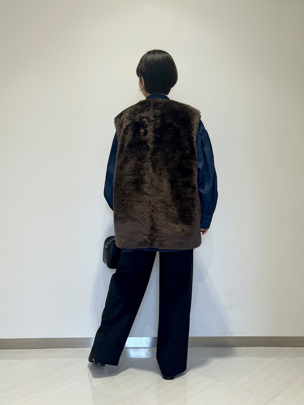 ブラック系のショルダーバッグ、ブラック系のスラックス、ブルー系のシャツ/ブラウスを着用したレディースの冬コーディネートの3枚目の写真