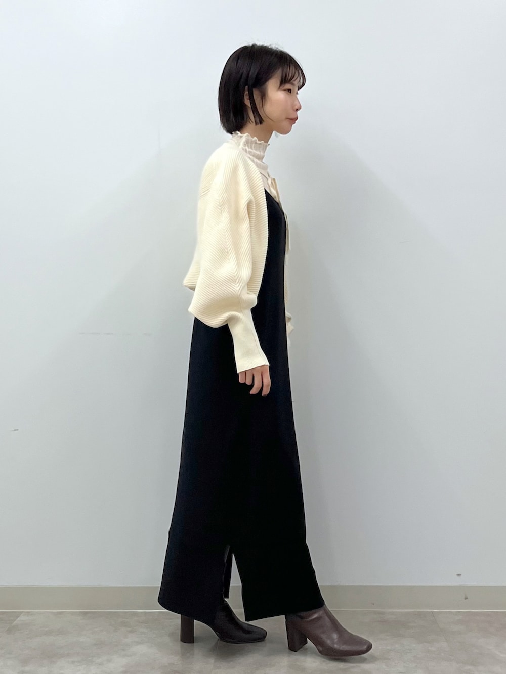 ブラック系のワンピース、ホワイト系のショルダーバッグ、ブラウン系のブーツを着用したレディースの冬コーディネートの4枚目の写真