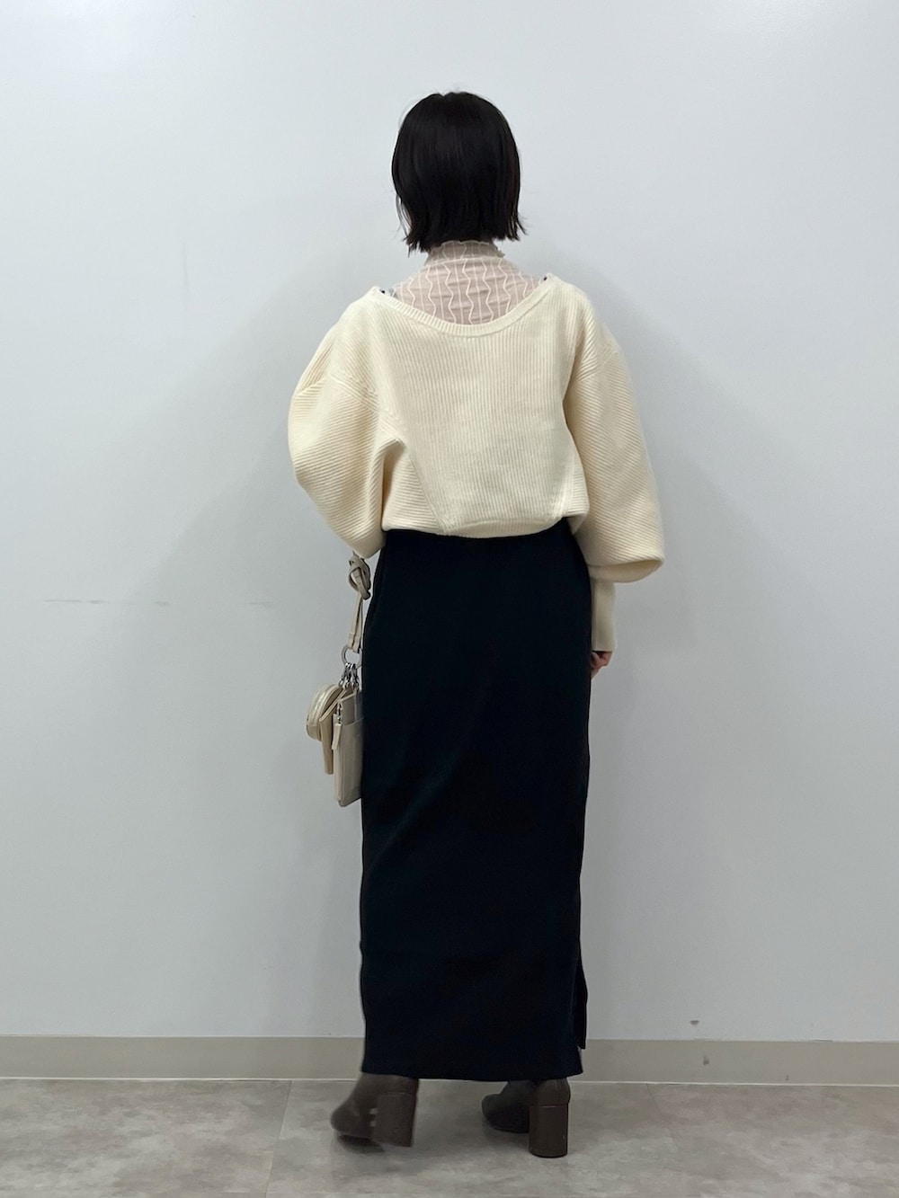 ブラック系のワンピース、ホワイト系のショルダーバッグ、ブラウン系のブーツを着用したレディースの冬コーディネートの3枚目の写真