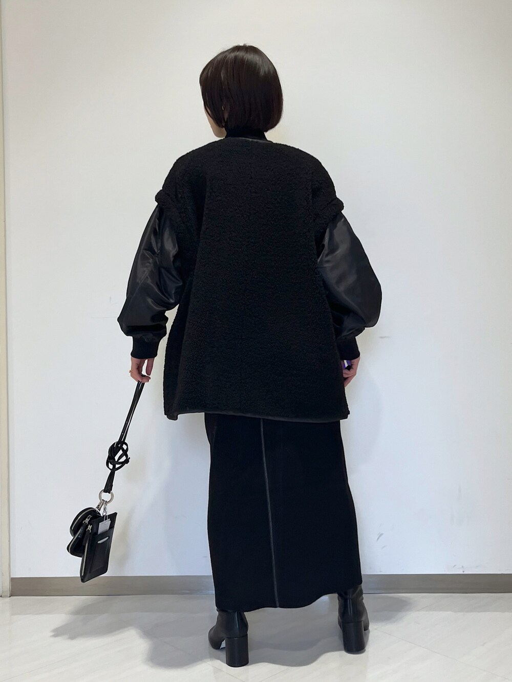 ブラック系のスカート、ブラック系のブルゾン、ブラック系のブーツを着用したレディースの冬コーディネートの3枚目の写真