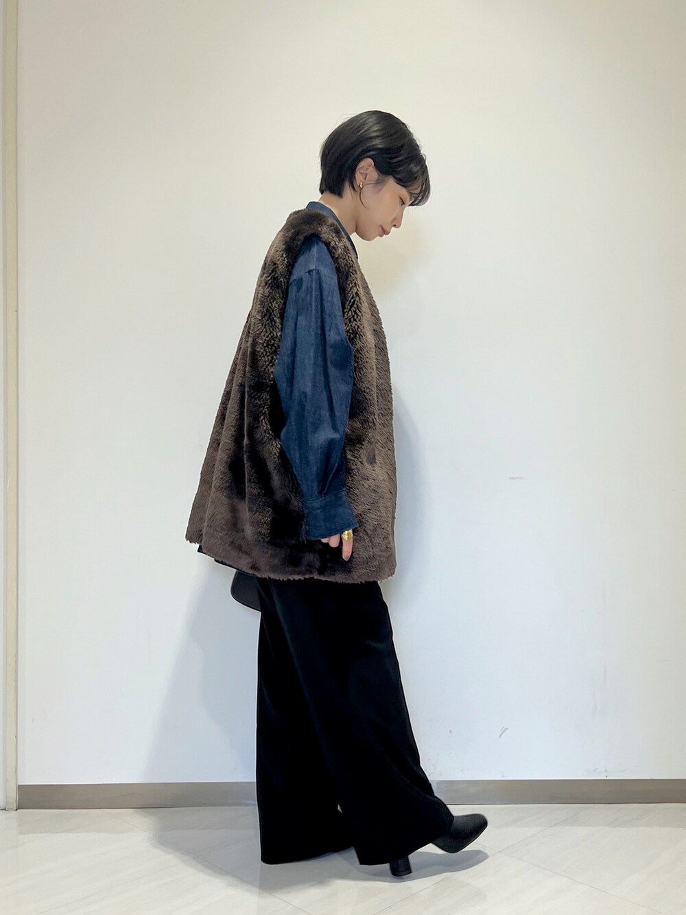 ブラック系のショルダーバッグ、ブラック系のスラックス、ブルー系のシャツ/ブラウスを着用したレディースの冬コーディネートの5枚目の写真