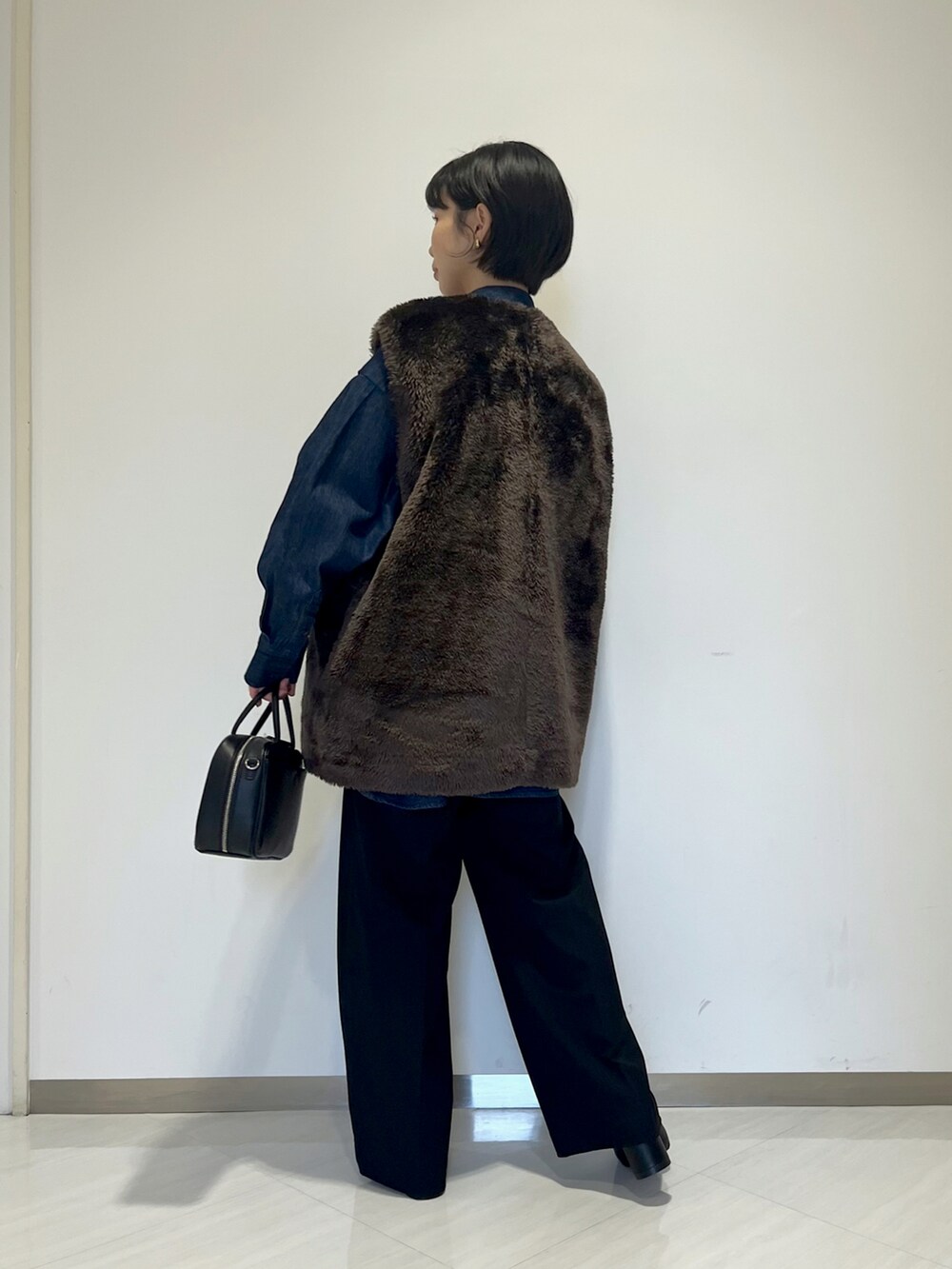 ブラック系のショルダーバッグ、ブラック系のスラックス、ブルー系のシャツ/ブラウスを着用したレディースの冬コーディネートの4枚目の写真