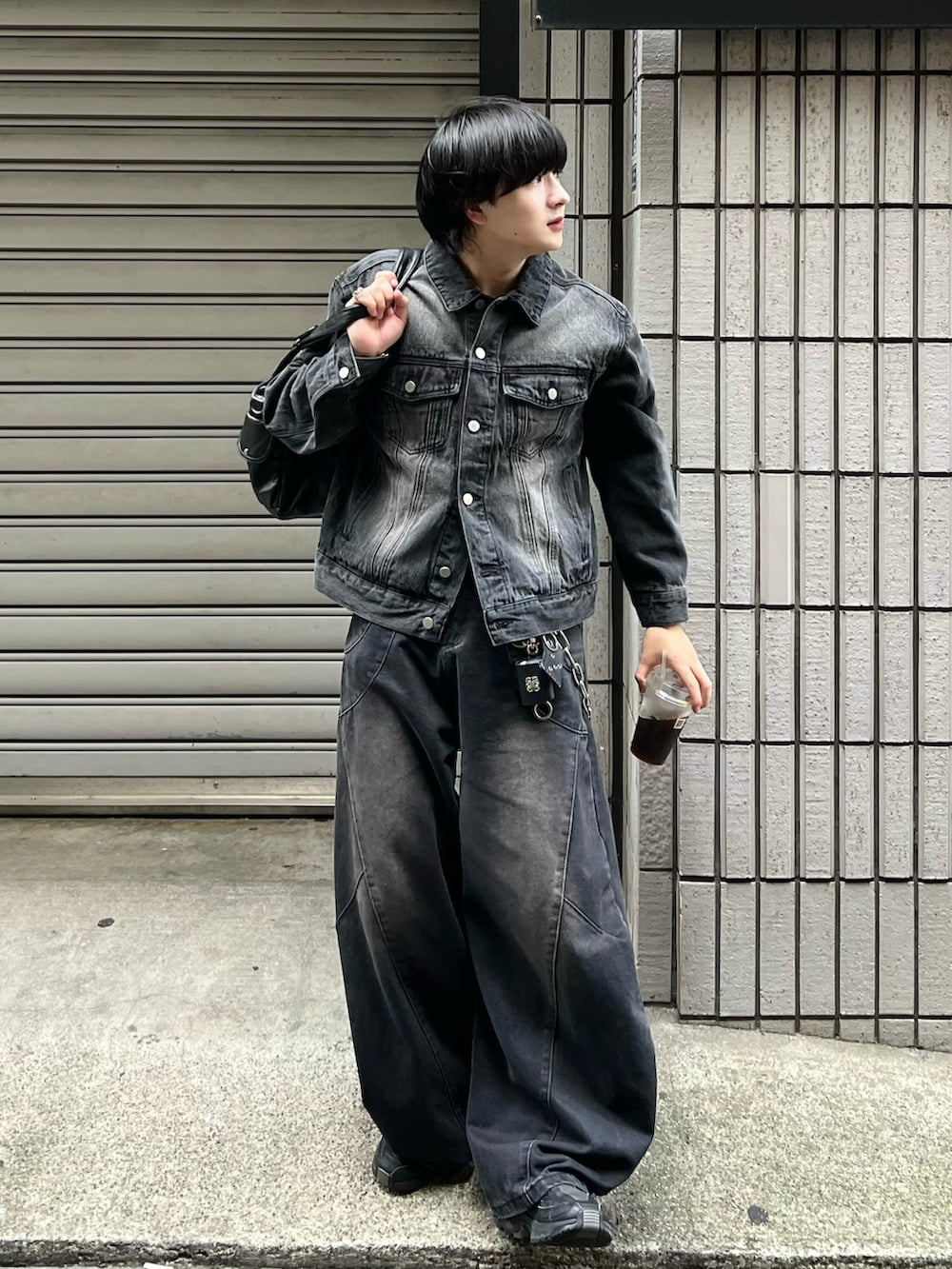 ブラック系のデニムジャケット、ブラック系のデニムパンツ、ブラック系のショルダーバッグを着用したメンズの秋コーディネートの2枚目の写真