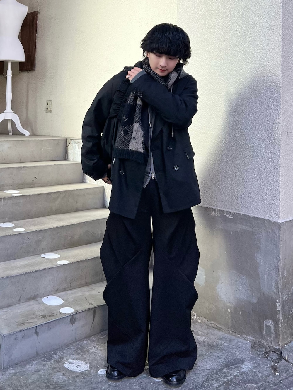 グレー系のパーカー、ブラック系のショルダーバッグ、ブラック系のスラックスを着用したメンズの冬コーディネートの2枚目の写真