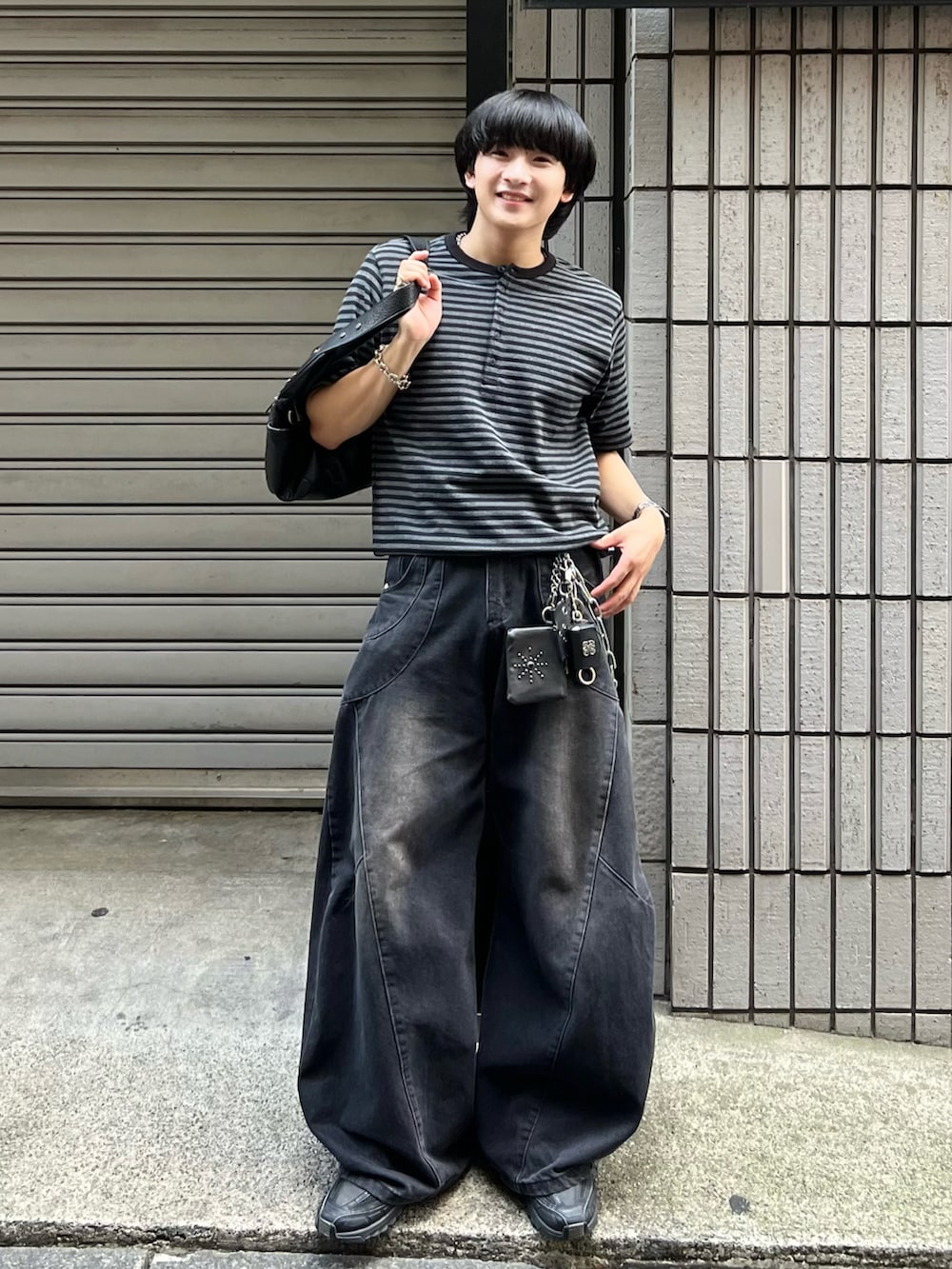 ブラック系のデニムパンツ、ブラック系のスニーカー、ブラック系のショルダーバッグを着用したメンズの秋コーディネートの2枚目の写真