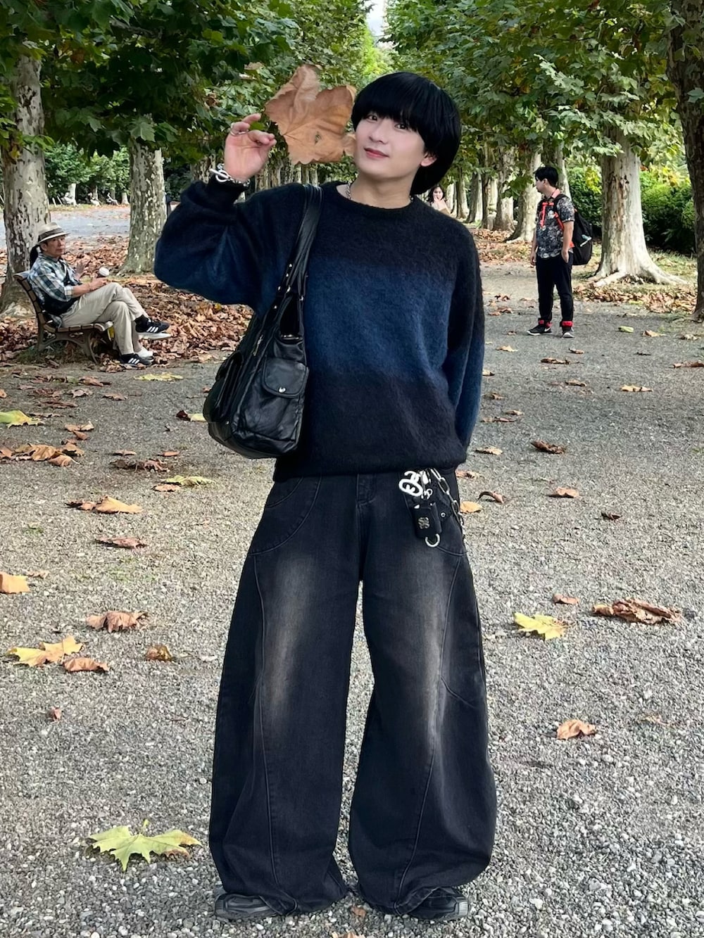 ブラック系のニット/セーター、ブラック系のデニムパンツ、ブラック系のショルダーバッグを着用したメンズの秋コーディネートの2枚目の写真