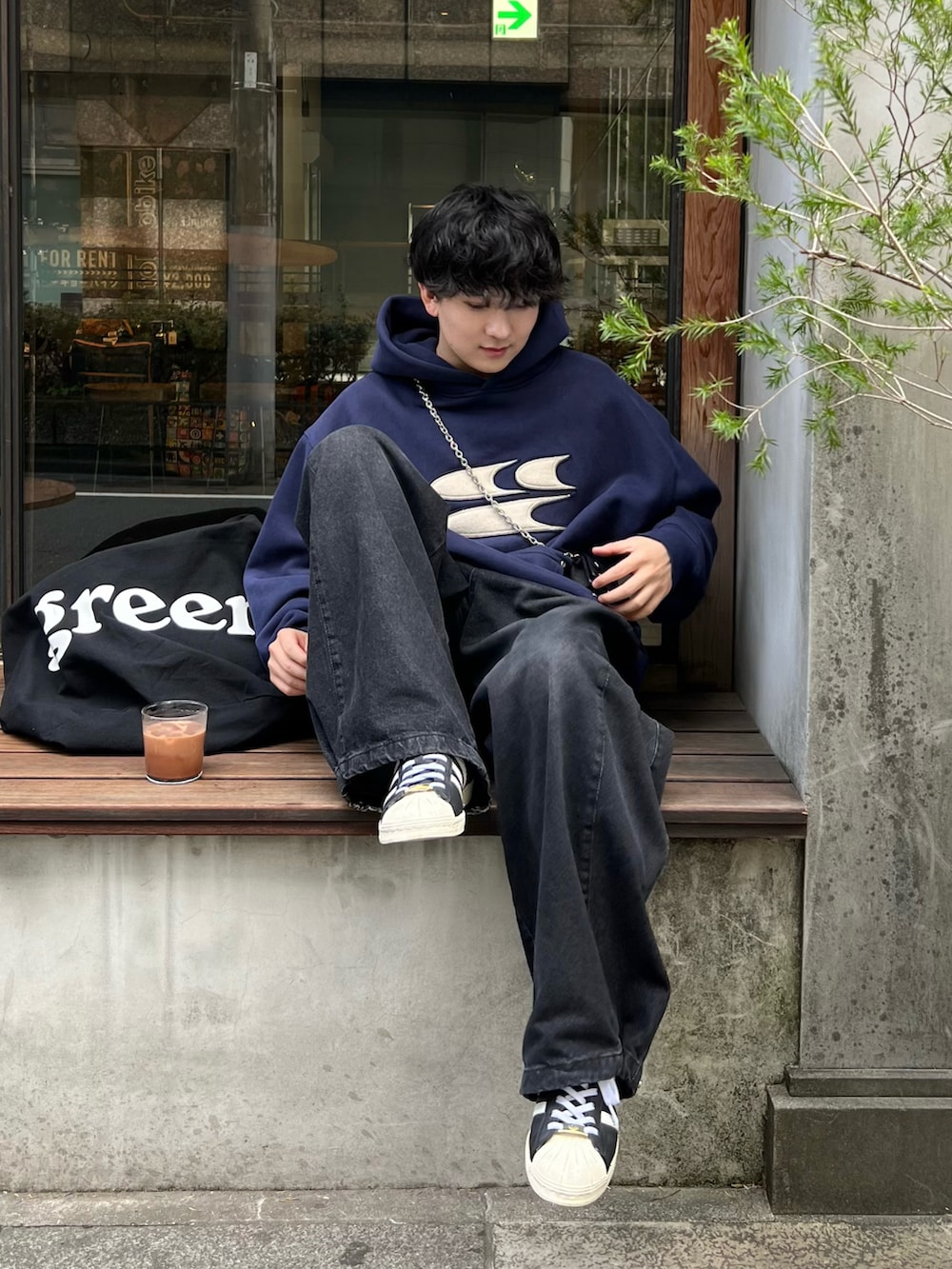 ブルー系のパーカー、ブラック系のトートバッグ、ブラック系のデニムパンツを着用したメンズの春コーディネートの3枚目の写真