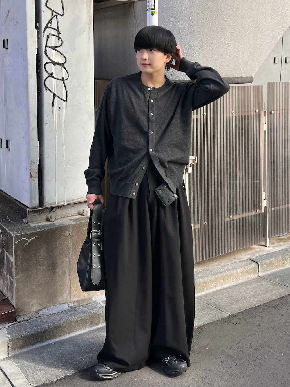 グレー系のカーディガン/ボレロ、ブラック系のハンドバッグ、ブラック系のスラックスを着用したメンズの春コーディネートの2枚目の写真