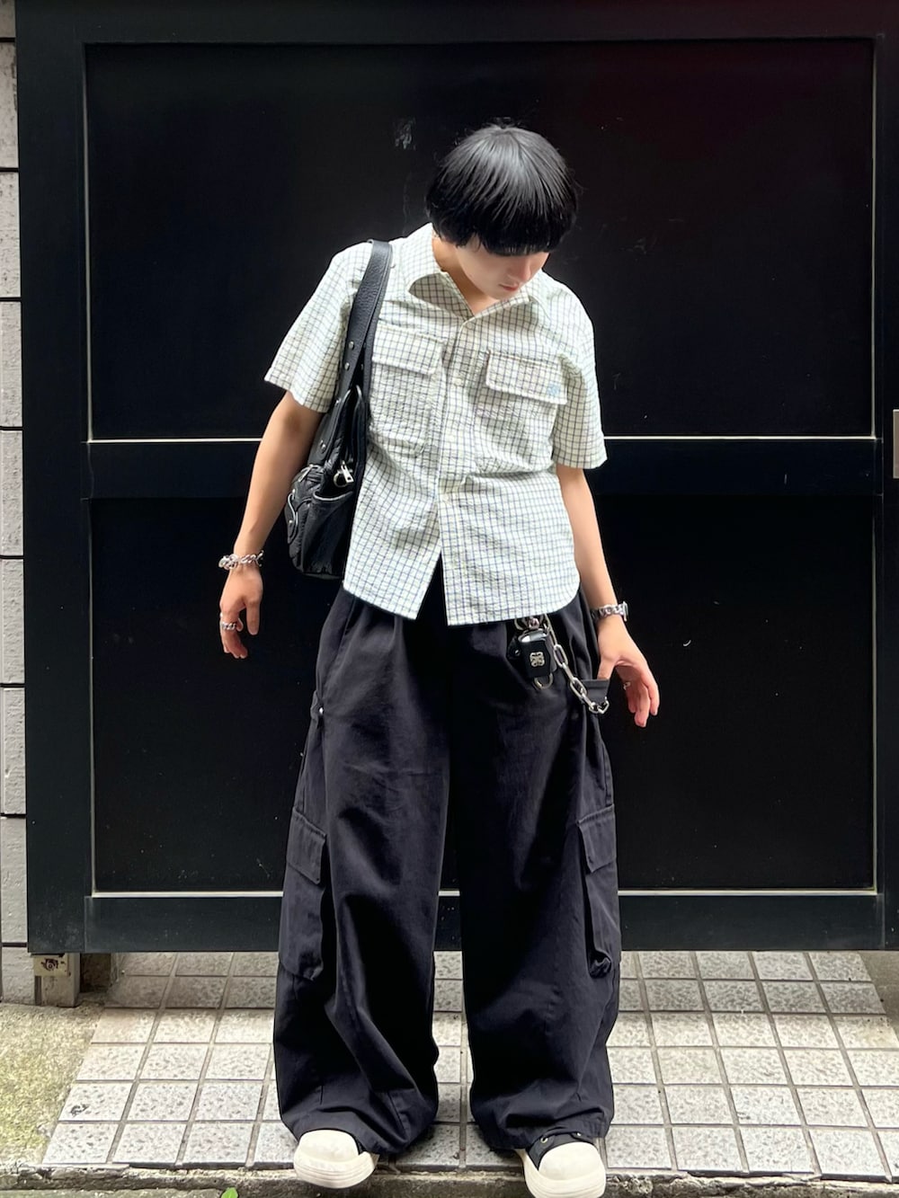 ブラック系のカーゴパンツ、ブラック系のショルダーバッグ、ブラック系のスニーカーを着用したメンズの夏コーディネートの2枚目の写真