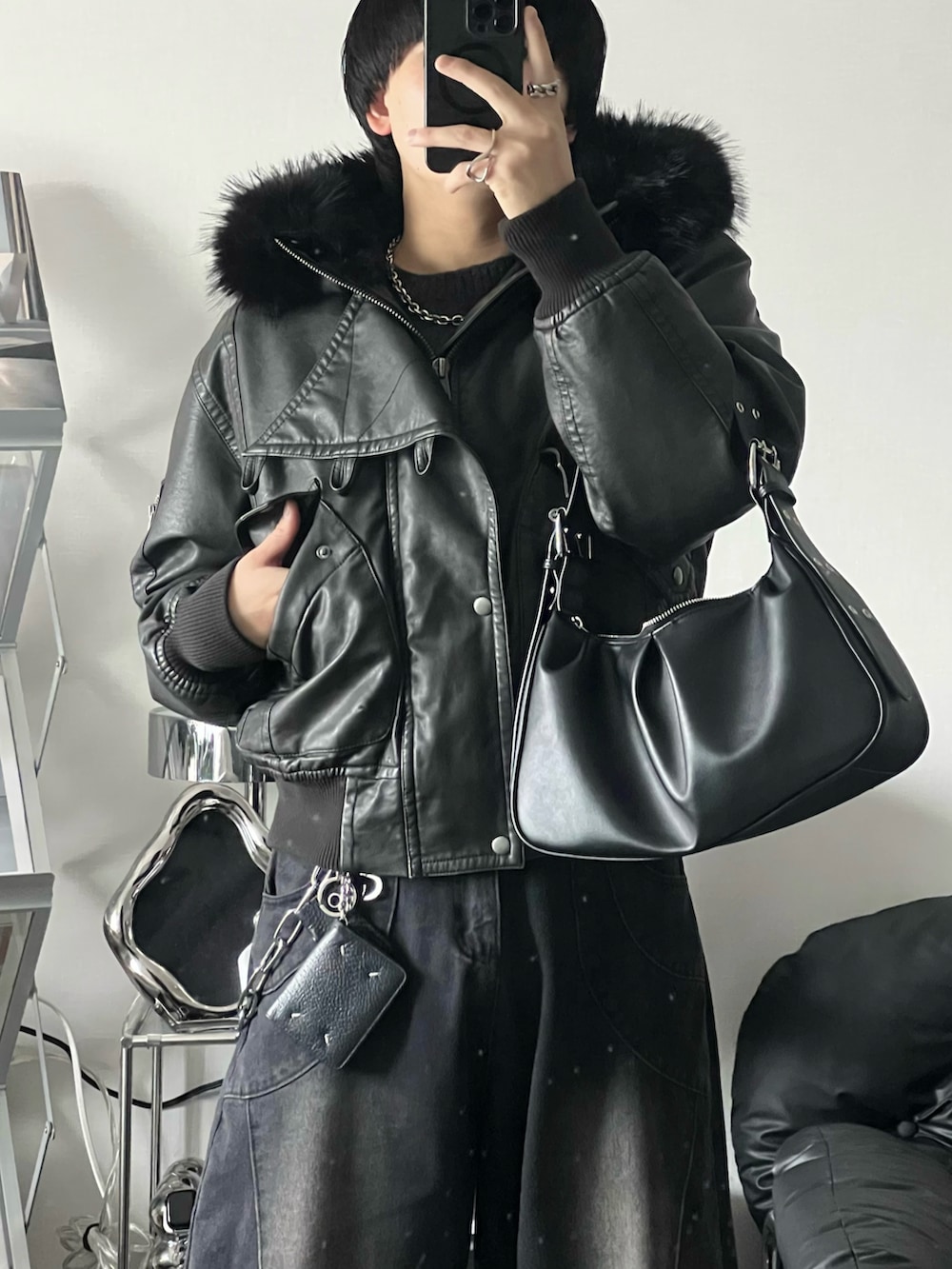 ブラック系のブルゾン、ブラック系のデニムパンツ、ブラック系のハンドバッグを着用したメンズの冬コーディネートの2枚目の写真