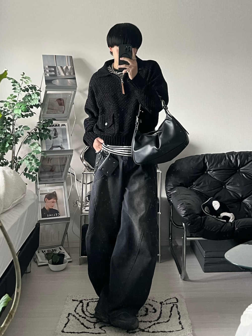ブラック系のハンドバッグ、ブラック系のニット/セーター、ブラック系のデニムパンツを着用したメンズの冬コーディネートの2枚目の写真