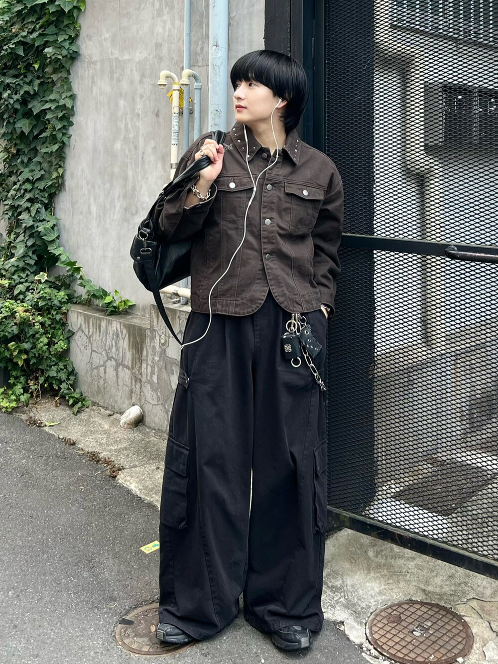 ブラック系のカーゴパンツ、ブラウン系のデニムジャケット、ブラック系のショルダーバッグを着用したメンズの秋コーディネートの2枚目の写真