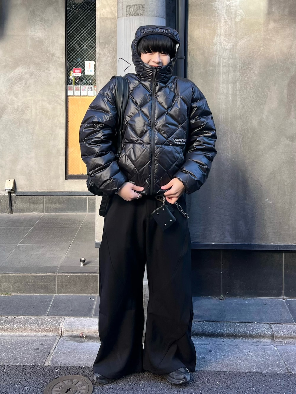 ブラック系のダウンジャケット/コート、ブラック系のスラックス、ブラック系のショルダーバッグを着用したメンズの冬コーディネートの2枚目の写真