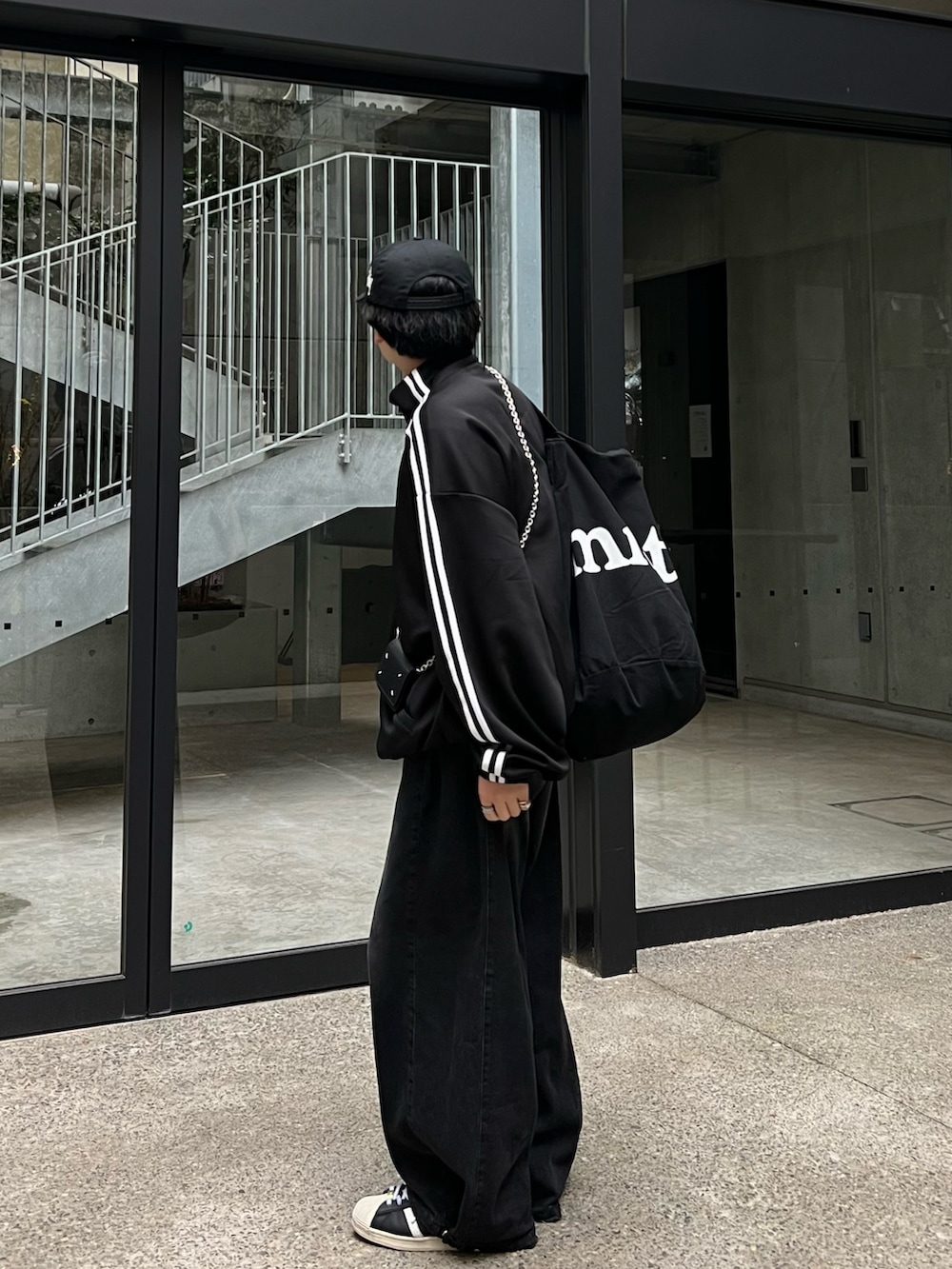 ブラック系のジャージ、ブラック系のトートバッグ、ブラック系のデニムパンツを着用したメンズの春コーディネートの3枚目の写真