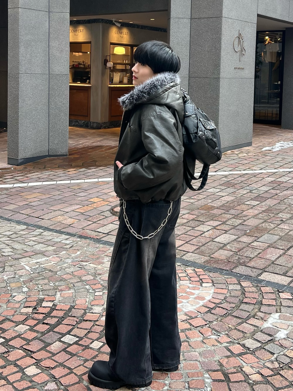 ブラック系のカーディガン/ボレロ、ブラック系のデニムパンツ、ブラック系のブーツを着用したメンズの冬コーディネートの3枚目の写真