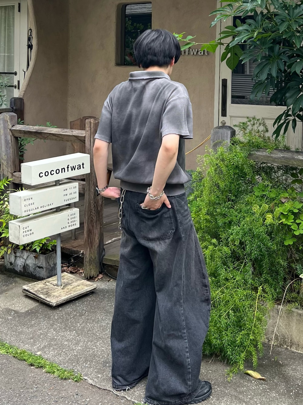 グレー系のポロシャツ、ブラック系のデニムパンツ、ブラック系のスニーカーを着用したメンズの夏コーディネートの3枚目の写真