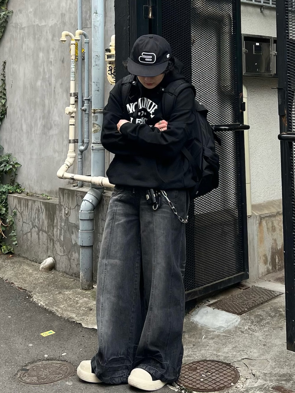ブラック系のパーカー、ブラック系のデニムパンツ、ブラック系のスニーカーを着用したメンズの春コーディネートの3枚目の写真