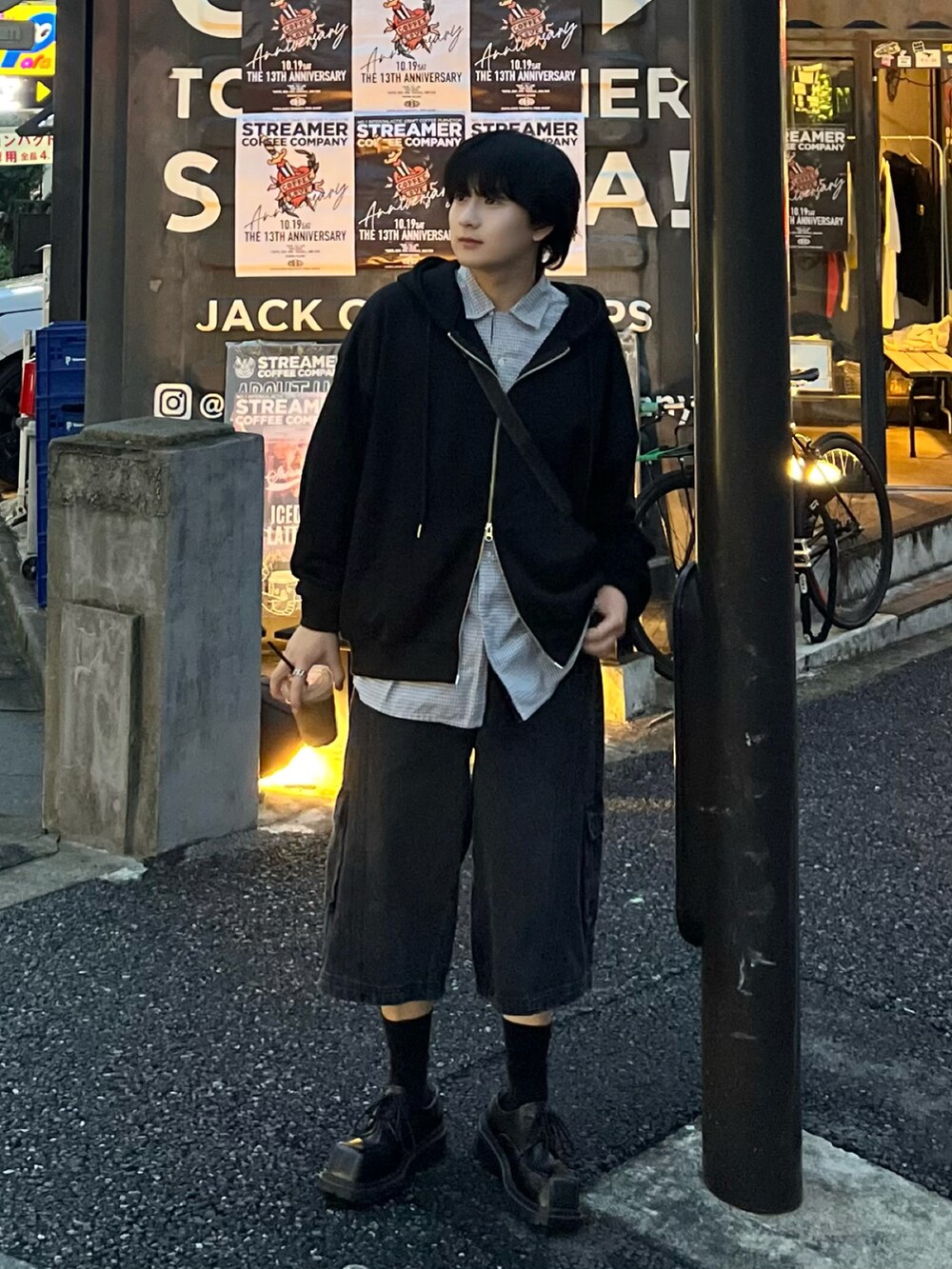 ブラック系のパーカー、グレー系のショルダーバッグ、ブラック系のデニムパンツを着用したメンズの秋コーディネートの2枚目の写真