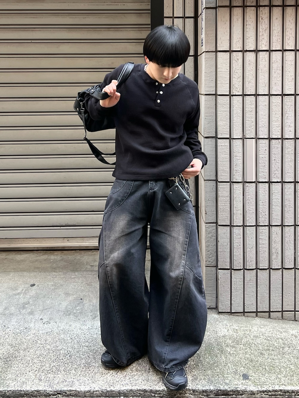 ブラック系のTシャツ/カットソー、ブラック系のデニムパンツ、ブラック系のショルダーバッグを着用したメンズの春コーディネートの3枚目の写真